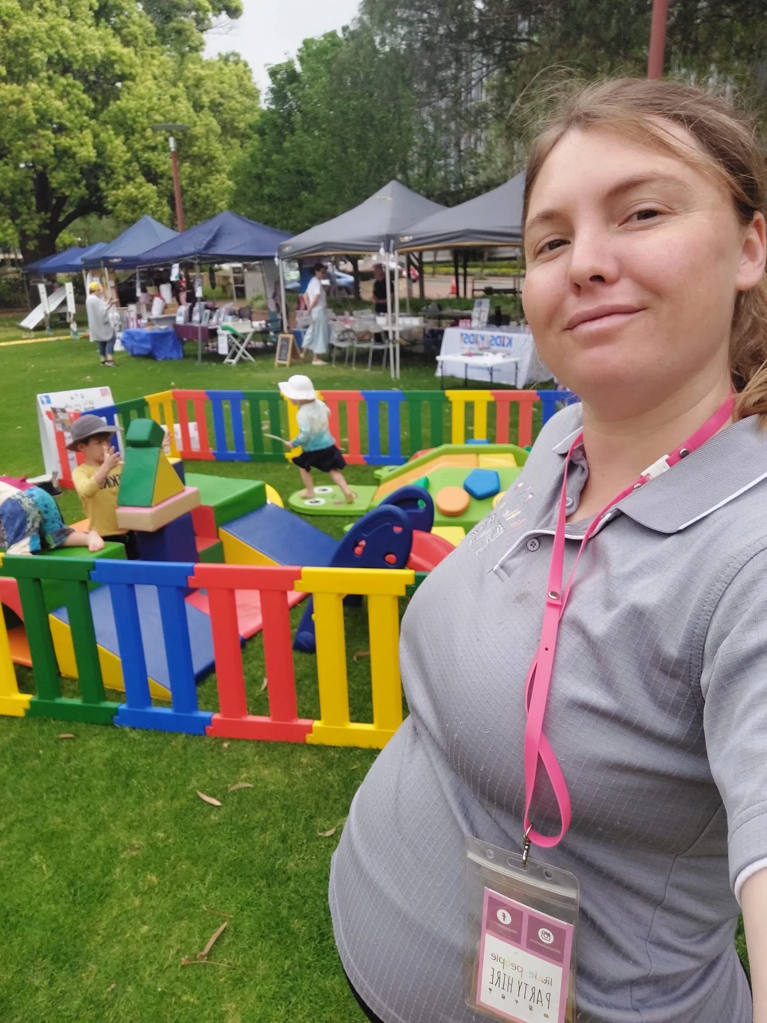 Sam at a community event with colourful soft play fencing behind her
